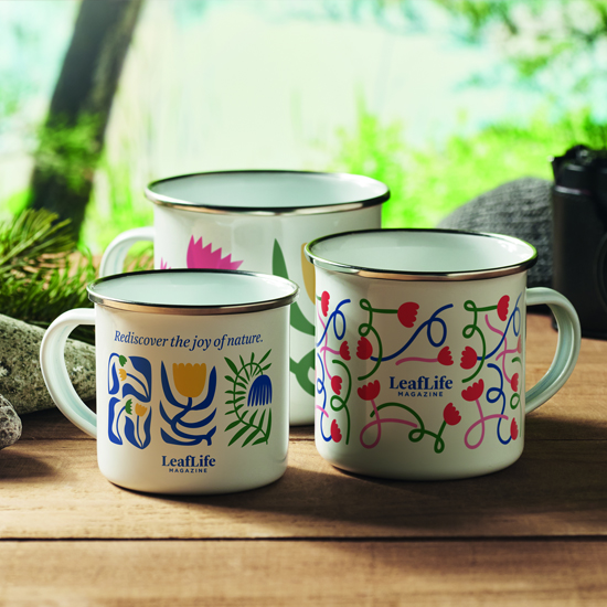 Kolorowe kubki emaliowane z nadrukiem ustawione przy ognisku podczas wyjazdu plenerowego