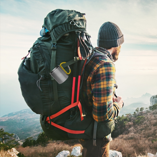 Kubek metalowy z karabińczykiem przypięty do plecaka turystycznego podczas wyprawy w góry
