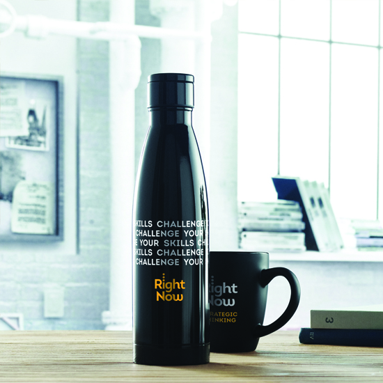 Czarna butelka termiczna z kolorowym nadrukiem logo firmy stojąca przy kubku na biurku w nowoczesnym biurze