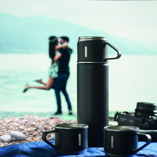 Czarny termos stalowy z trzema kubkami na plaży podczas wyjazdu — zestaw reklamowy z logo firmy